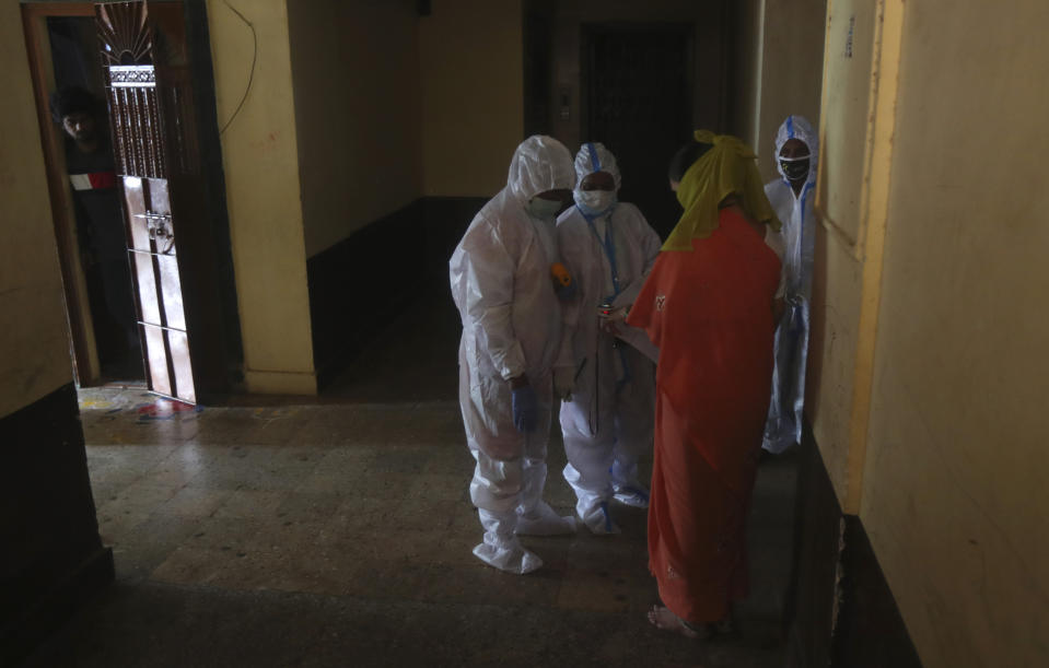 Health workers screen people for COVID-19 symptoms at a residential building in Dharavi, one of Asia's biggest slums, in Mumbai, India, Friday, Aug. 7, 2020. As India hit another grim milestone in the coronavirus pandemic on Friday, crossing 2 million cases and more than 41,000 deaths, community health volunteers went on strike complaining they were ill-equipped to respond to the wave of infection in rural areas. (AP Photo/Rafiq Maqbool)