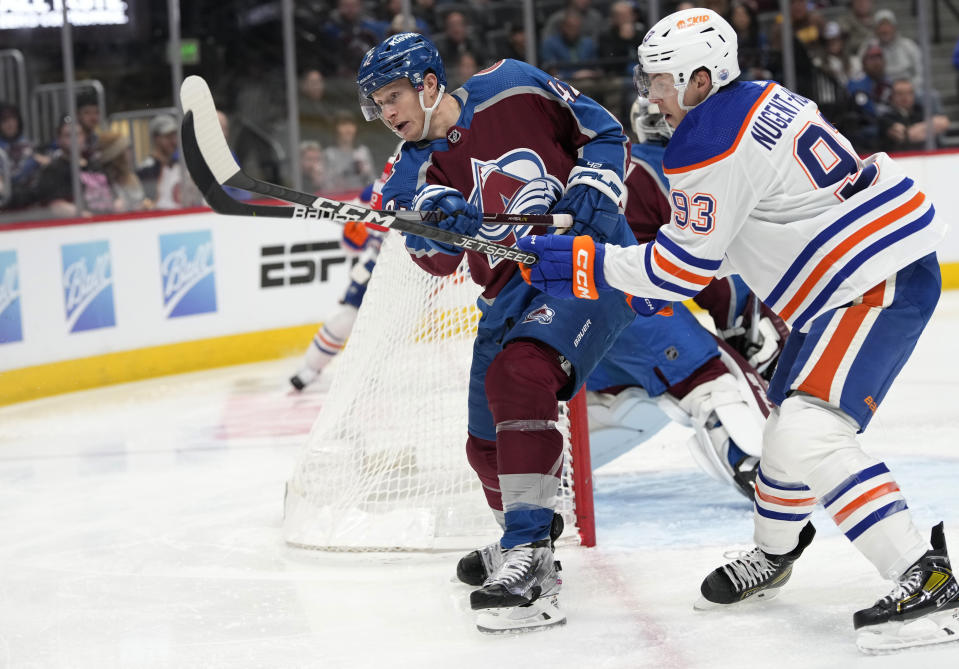 Colorado Avalanche defenseman Josh Manson, left, clears the puck as Edmonton Oilers center Ryan Nugent-Hopkins, right, defends in the second period of an NHL hockey game Sunday, Feb. 19, 2023, in Denver. (AP Photo/David Zalubowski)