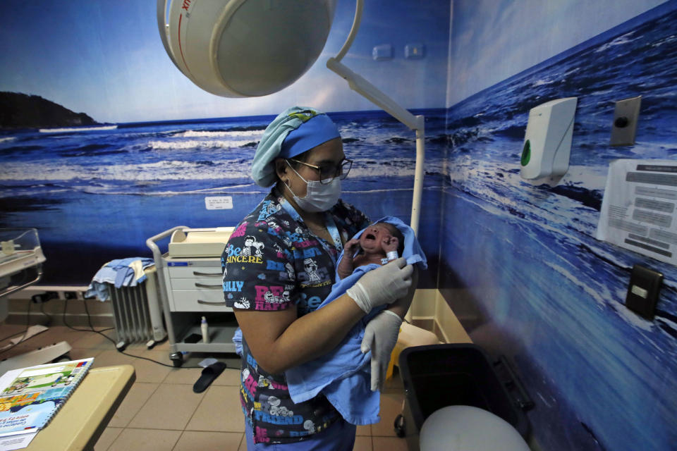 Namunkura Fernandez Aucapan is taken by a nurse to be tested after being born at the San Jose de Osorno Base Hospital in Osorno, Chile, Saturday, Aug. 20, 2022. The largest public hospital in Osorno is finding new ways to incorporate Indigenous health care practices, such as having a machi, or Mapuche spiritual guide, help with delivery. (AP Photo/Luis Hidalgo)