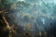 This photo provided by the fire brigade of the Gironde region SDIS 33, (Departmental fire and rescue service 33) shows firefighters on a track next to the smoldering remains of a blaze near Saint-Magne, south of Bordeaux, southwestern France, Thursday, Aug. 11, 2022. (SDIS 33 via AP)