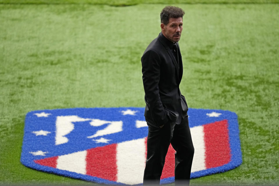 El técnico del Atlético de Madrid Diego Simeone frente al emblema oficial del club para recibir el trofeo de campeones de la Liga española en el estadio Wanda Metropolitano en Madrid, el domingo 23 de mayo de 2021. (AP Foto/Manu Fernández)