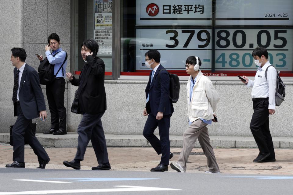 People walk in front of an electronic stock board showing Japan's Nikkei 225 index at a securities firm Thursday, April 25, 2024, in Tokyo. (AP Photo/Eugene Hoshiko)