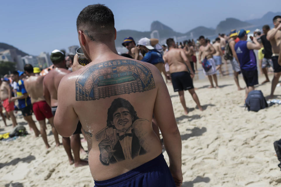 A Boca Juniors soccer fan's back is covered with a tattoo of the late Argentine soccer legend Diego Maradona on Copacabana beach where Boca Juniors fans gather the day before Boca faces Brazil's Fluminense at a Copa Libertadores championship match in Rio de Janeiro, Brazil, Friday, Nov. 3, 2023. (AP Photo/Bruna Prado)