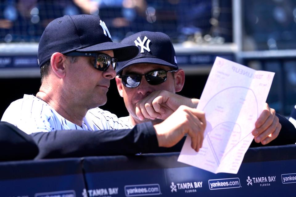 New York Yankees manager Aaron Boone, left, and bench coach Carlos Mendoza, right, look at the lineup before a spring training baseball game against the Detroit Tigers, Sunday, March 20, 2022, in Tampa, Fla.