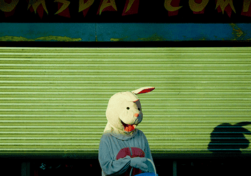 A man in a bunny costume stands outside a shuttered storefront