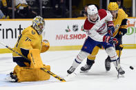 Montreal Canadiens right wing Cole Caufield (22) and Nashville Predators defenseman Dante Fabbro (57) vie for the puck in front of Predators goaltender Juuse Saros (74) during the first period of an NHL hockey game Saturday, Dec. 4, 2021, in Nashville, Tenn. (AP Photo/Mark Zaleski)