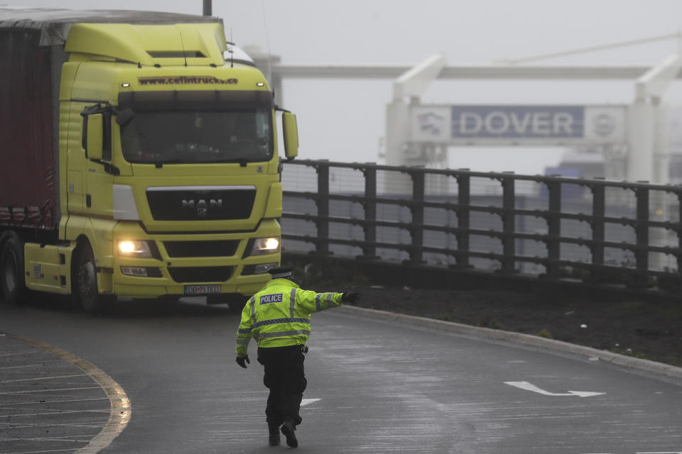 A police officer directs traffic at the entrance to the closed ferry terminal in Dover, England, Monday, Dec. 21, 2020, after the Port of Dover was closed and access to the Eurotunnel terminal suspended following the French government's announcement. France banned all travel from the UK for 48 hours from midnight Sunday, including trucks carrying freight through the tunnel under the English Channel or from the port of Dover on England's south coast. (AP Photo/Kirsty Wigglesworth)