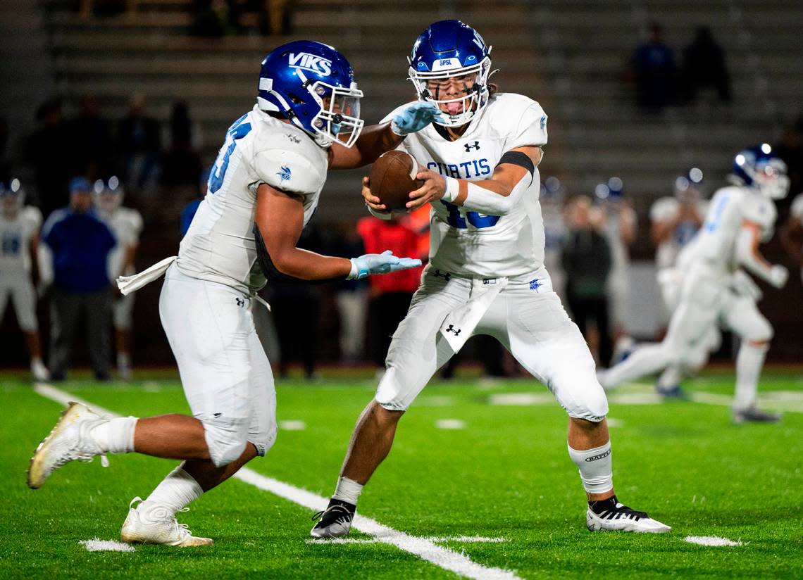 Curtis quarterback Rocco Koch (15) fakes handing the ball off to Curtis running back Lyndon Tanoa (33) during the third quarter of a game against Emerald Ridge at Sparks Stadium in Puyallup, Wash. on Sept. 22, 2022. Emerald Ridge defeated Curtis 42-13.