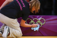 A volunteer polishes the rings on the medal stand at the judo on Day two of the London 2012 Olympic Games at ExCeL on July 29, 2012 in London, Englan (Photo by Michael Steele/Getty Images)