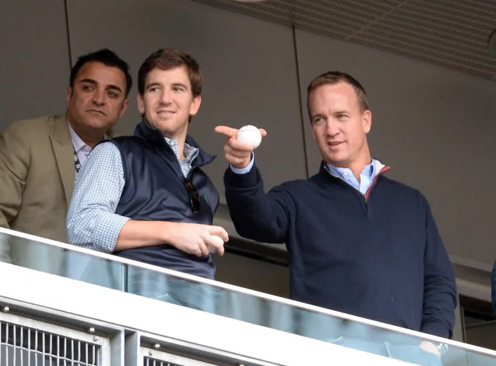 Eli Manning and Peyton Manning watch the game between the New York Yankees and Tampa Bay Rays at Yankee Stadium.