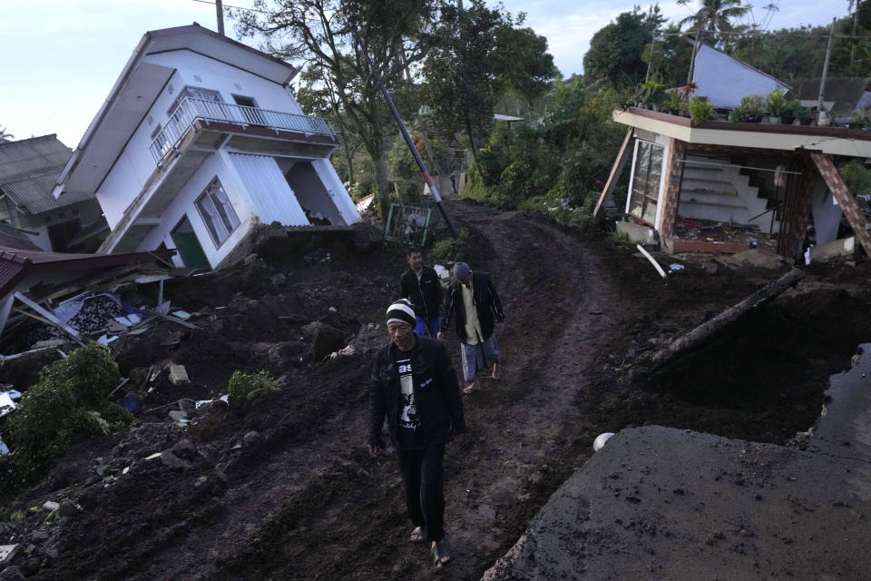 Residents walk past ruined homes damaged in Monday's earthquake in Cianjur, West Java, Indonesia, Thursday, Nov. 24, 2022. The 5.6 magnitude earthquake left hundreds dead, injures and missing as buildings crumbled and terrified residents ran for their lives on Indonesia's main island of Java. (AP Photo/Tatan Syuflana)