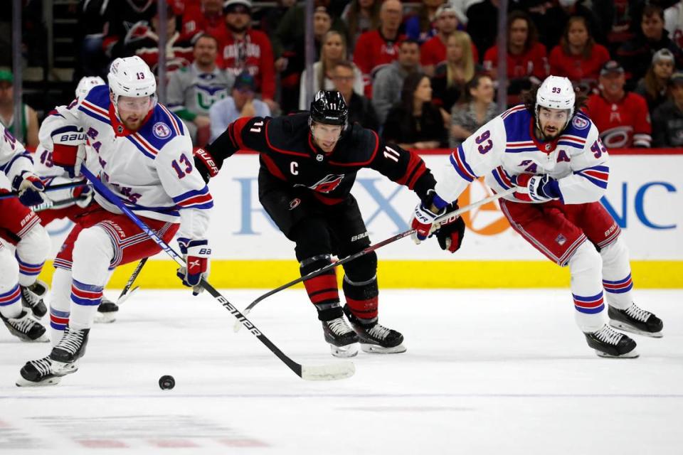 New York Rangers’ Alexis Lafrenière (13) gathers in the puck after teammate Mika Zibanejad (93) took it away from Carolina Hurricanes’ Jordan Staal (11) during the first period of an NHL hockey game in Raleigh, N.C., Sunday, March 20, 2022. (AP Photo/Karl B DeBlaker)