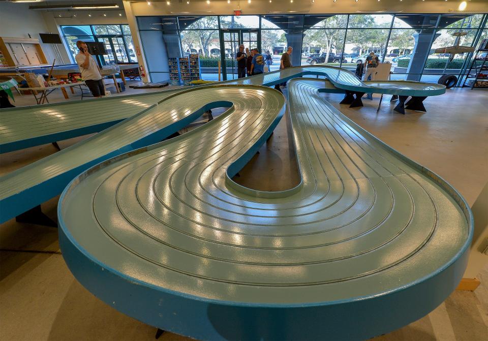 Volunteers help finish assembly of the Big Blue King Track, the largest track at the Slot Car Raceway and Hobby Shop on Feb. 4, 2023, in the Outlets Mall in Vero Beach. the track still needs to be braided, adding the metal braid that distributes the electric current to the cars. The track has 155 feet of racing fun for the 1/24 scale cars. 