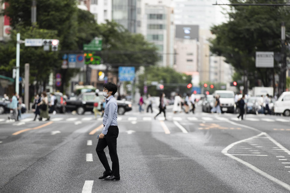 A man wearing a face mask walks across a street in the famed Ginza shopping neighborhood in Tokyo on Friday, May 21, 2021. Japan has approved the use of two new vaccines - Moderna and AstraZeneca - hours ahead of an expansion of a state of coronavirus emergency that will cover roughly 40% of the population. It’s the latest effort to contain a worrying surge in infections nine weeks ahead of the opening of the Tokyo Olympics.(AP Photo/Hiro Komae)