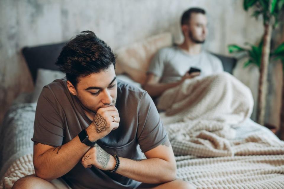 two men sitting apart from each other in bed