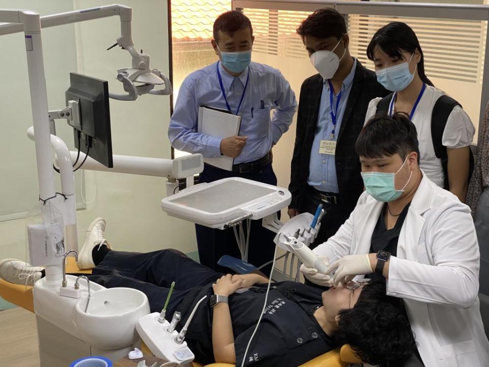 東南亞20餘名牙醫師前來高醫交流參訪，高醫牙科部主治醫師劉致德(右)操作口腔數位掃描機供外籍牙醫師觀摩。　（記者王正平攝）
