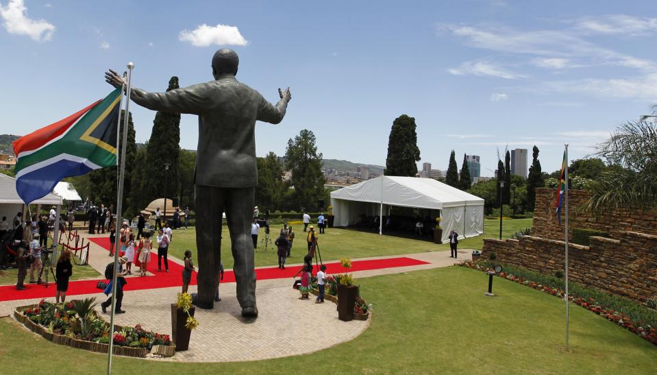 People stand near the 9-metre bronze statue of Nelson Mandela as it is unveiled at the Union Buildings in Pretoria