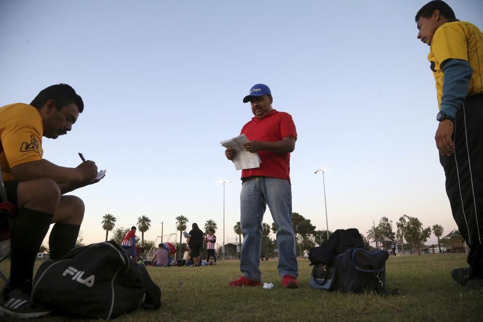 Antonio Velasquez, middle, a pastor and director of the Maya Chapin soccer league of over 108 teams, gives referees their game assignments Wednesday, April 17, 2019, in Phoenix. The Pentecostal pastor was a teenager in 1990, fleeing Guatemala’s civil war when smugglers randomly dropped him and other teens near Phoenix, where he initially worked in agriculture and lived in a trailer with others from the western highlands. (AP Photo/Ross D. Franklin)