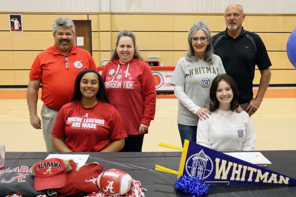 Brooklyn Bull and Emma Engler sit with their families behind as they sign Certificates of Intent to colleges after graduating from Ascension Academy Monday afternoon.