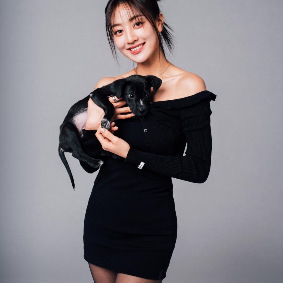 Woman in an off-shoulder dress holds a small dog