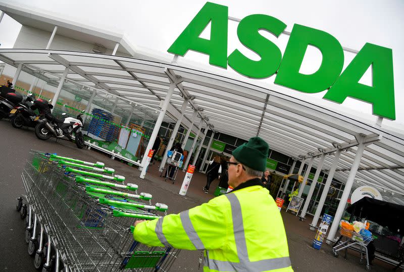 FILE PHOTO: A worker pushes shopping trolleys at an Asda store in London