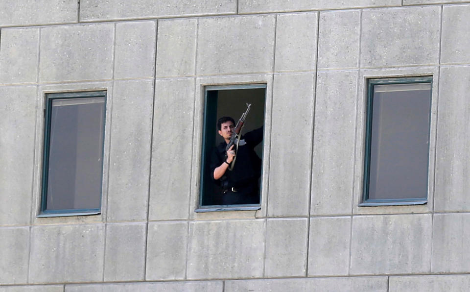 An armed man stands in a window of the parliament