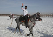 A rider, member of the Dadas (Comrades) local sporting club, waves to the crowd following a game of Cirit, a traditional Turkish equestrian sport that dates back to the martial horsemen who spearheaded the historical conquests of central Asia's Turkic tribes, between the Comrades and the Experts local sporting clubs, in Erzurum, eastern Turkey, Friday, March 5, 2021. The game that was developed more than a 1,000 years ago, revolves around a rider trying to spear his or her opponent with a "javelin" - these days, a rubber-tipped, 100 centimeter (40 inch) length of wood. A rider from each opposing team, which can number up to a dozen players, face each other, alternately acting as the thrower and the rider being chased. Cirit was popular within the Ottoman empire, before it was banned as in the early 19th century. However, its popularity returned as is now one of many traditional sports encouraged by the government and tournaments are often arranged during festivals or to celebrate weddings. (AP Photo/Kenan Asyali)