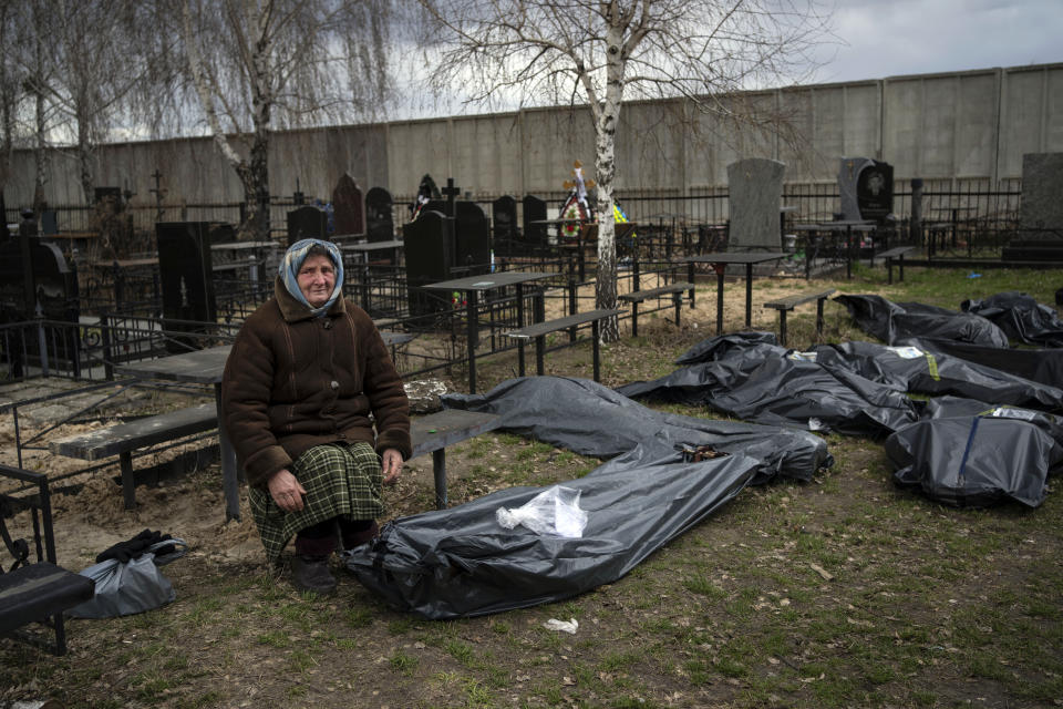 Nadiya Trubchaninova, 70, sits next to a plastic bag that contains the body of her son Vadym Trubchaninov, 48, who was killed by Russian soldiers in Bucha on March 30, in the outskirts of Kyiv, Ukraine, Tuesday, April 12, 2022. (AP Photo/Rodrigo Abd)