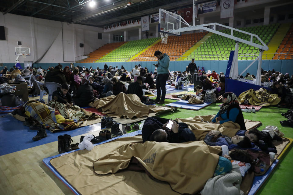 People gather inside a sports hall to spend the night following Friday's earthquake that destroyed their houses, in Elazig, eastern Turkey, late Saturday, Jan. 25, 2020. More than 24 hours after a powerful earthquake hit eastern Turkey rescuers continued to pull survivors from under collapsed buildings Sunday. (Ugur Can/DHA via AP)