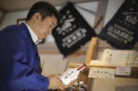 FILE - In this March 5, 2015, file photo, Michihiro Kono, president of Yagisawa Shoten Co., holds his company's soy sauce bottle, named "the miracle," at his company's new headquarters in Rikuzentakata, Iwate Prefecture, northeastern Japan. Just a month after a tsunami smashed into the city of Rikuzentakata, soy sauce maker Kono inherited his family's two-century-old business from his father. (AP Photo/Eugene Hoshiko, File)