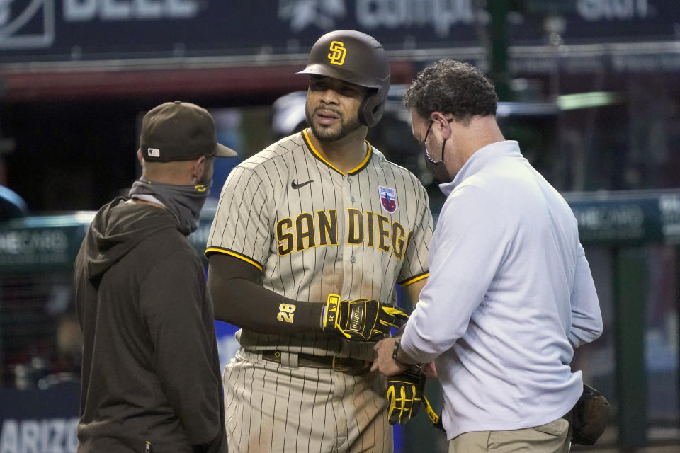 San Diego Padres' Tommy Pham, center, talks with trainers in the ninth inning during a baseball game against the Arizona Diamondbacks, Sunday, Aug 16, 2020, in Phoenix. Pham would leave the game with a two-strike count. (AP Photo/Rick Scuteri)