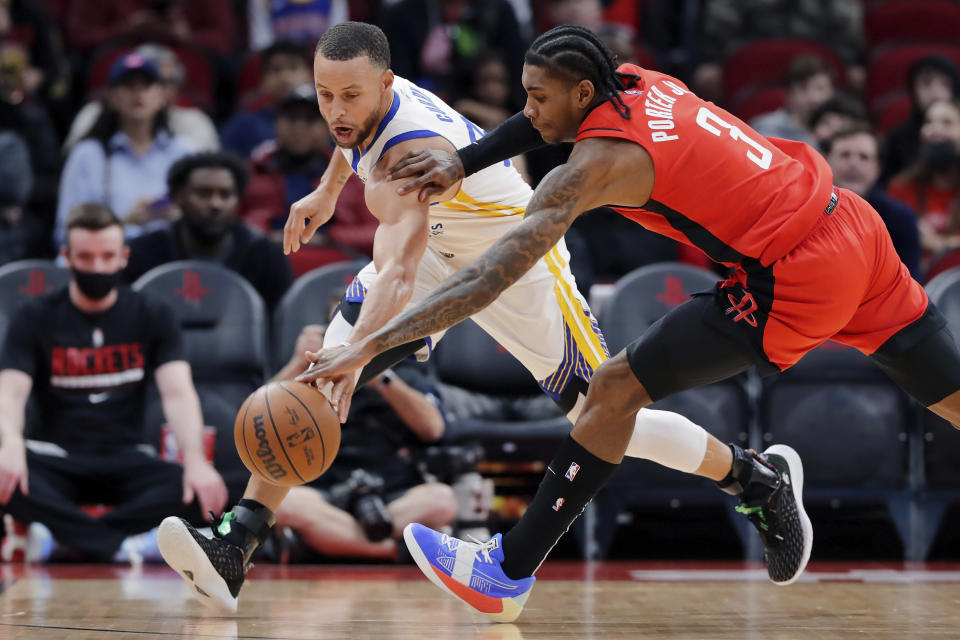 Golden State Warriors guard Stephen Curry, left, and Houston Rockets guard Kevin Porter Jr. (3) battle for the ball during the first half of an NBA basketball game Monday, Jan. 31, 2022, in Houston. (AP Photo/Michael Wyke)