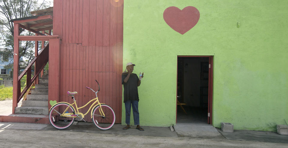 In this Sept. 11, 2013 photo, a man stands outside the shopping center in Bimini, Bahamas. Every time a cruise ship docks in Bimini, the population of this tiny archipelago just 50 miles off the coast of Miami could nearly double. That may be profitable for a place that lives off tourism. But many worry the recent launch of a new cruise line disgorging hundreds of visitors each day could be too much of a good thing. (AP Photo/J Pat Carter)