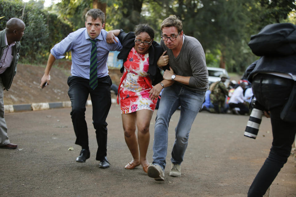 People take cover after an attack on a hotel, in Nairobi, Kenya, Tuesday, Jan. 15, 2019. Extremists launched a deadly attack on a luxury hotel in Kenya's capital Tuesday, sending people fleeing in panic as explosions and heavy gunfire reverberated through the complex. A police officer said he saw bodies, "but there was no time to count the dead." (AP Photo/Brian Inganga)