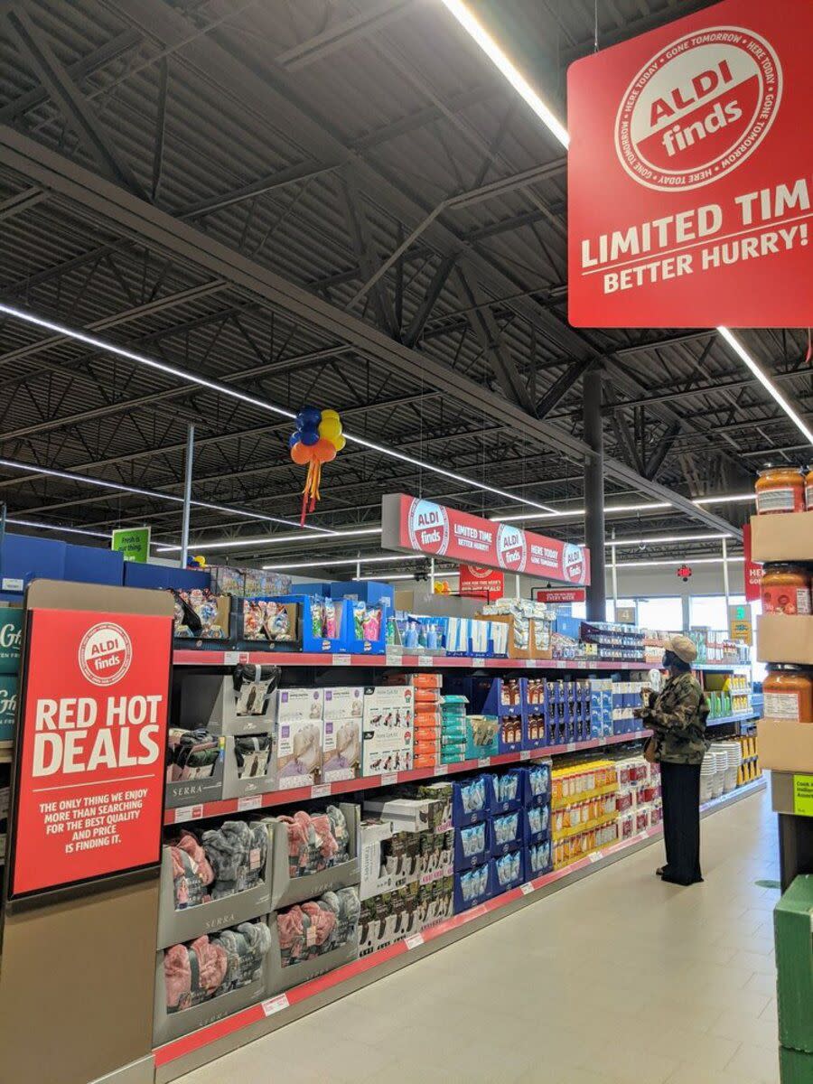 'Aldi Finds' section at Aldi, Gilbert, Arizona, one person looking at an entire aisle of deals, clean and brightly lit