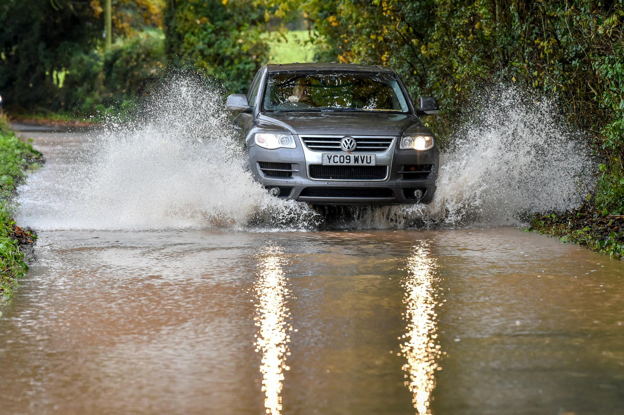 A car drives through floodwater after water has run off fields surrounding Clyst St Mary, Exeter, and flooded the roads after heavy rain. (Photo by Ben Birchall/PA Images via Getty Images)