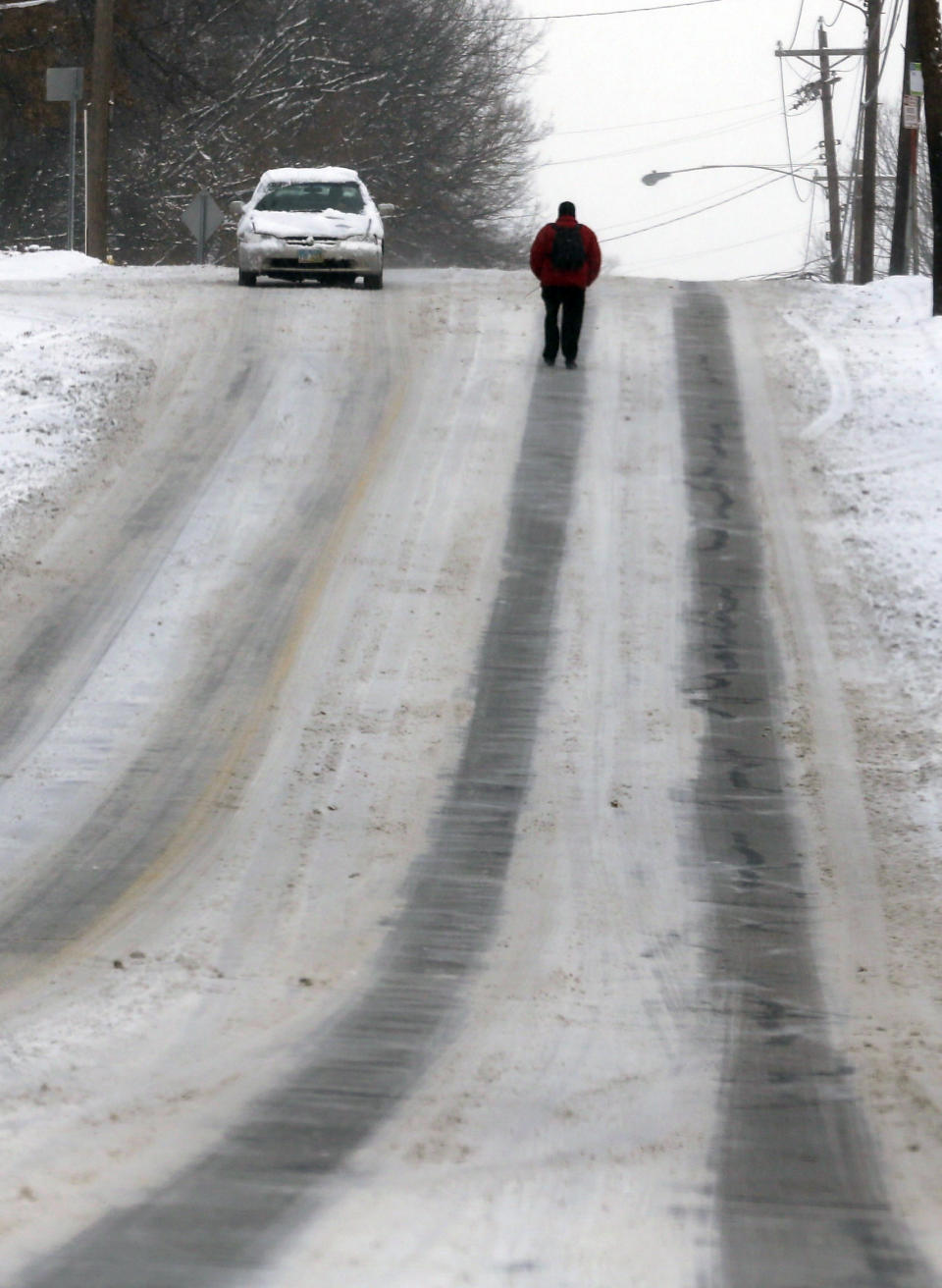 A pedestrian walks in the middle of a road to avoid snow covered sidewalks Tuesday, Jan. 21, 2014, in Cincinnati. The Cincinnati area received around three to five inches of snow. (AP Photo/Al Behrman)