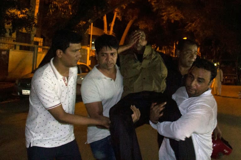 People assist an injured man near the Holey Artisan Bakery restaurant during an armed attack in Dhaka's diplomatic district