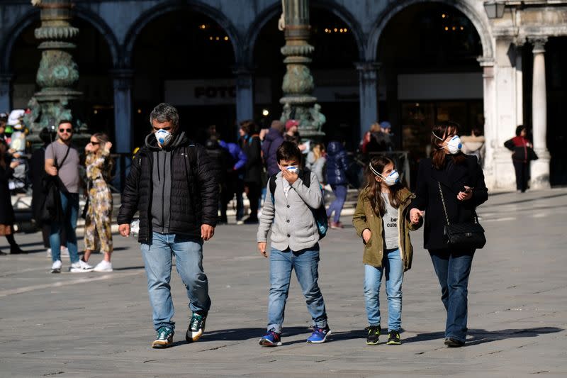 Tourists wearing protective masks walk through Saint Mark's Square in Venice as Italy battles a coronavirus outbreak