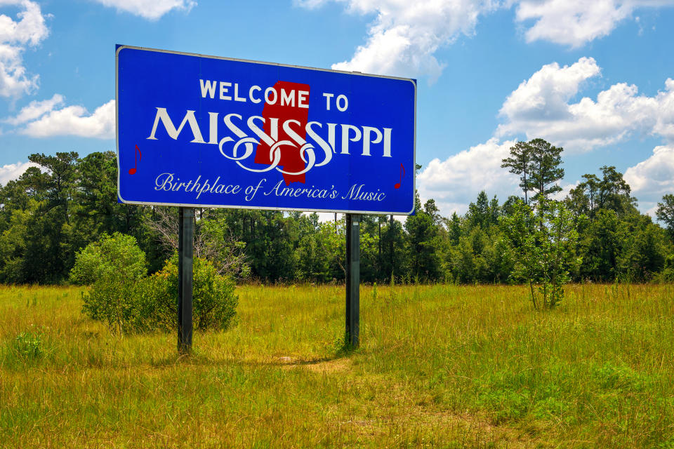 Welcome sign reading "Welcome to Mississippi, Birthplace of America's Music" with trees and sky in the background
