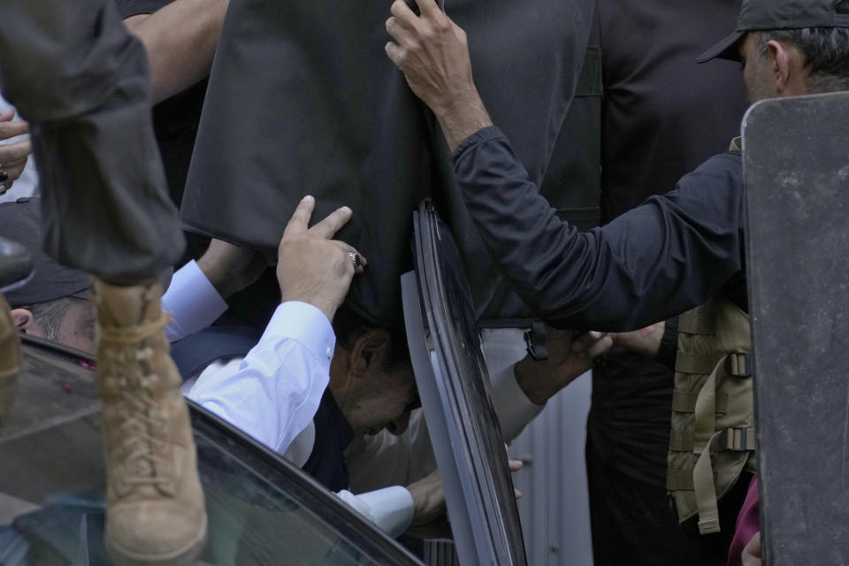 Security personnel hold bulletproof shields to protect former Prime Minister Imran Khan as he arrives to appear in a court, in Islamabad, Pakistan, Monday, March 27, 2023. A Pakistani court ruled in defense of former Prime Minister Khan, granting him protection from arrest as lawsuits mounted against the ousted premier, with police charging him with incitement to violence in several cases when his followers clashed with the security forces this month. (AP Photo/Anjum Naveed)