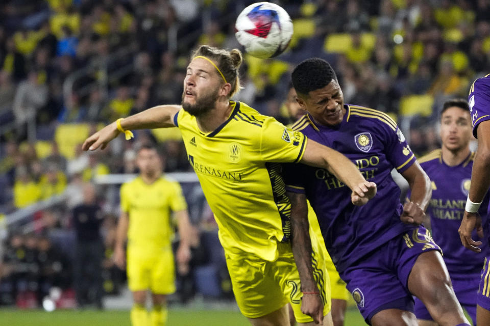 Nashville SC defender Walker Zimmerman, left, heads the ball past Orlando City midfielder Wilder Cartagena, right, during the first half of an MLS playoff soccer match Tuesday, Nov. 7, 2023, in Nashville, Tenn. (AP Photo/George Walker IV)