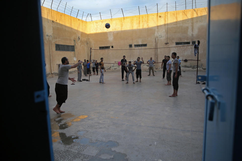 FILE - In this April 3, 2018 file, photo, prisoners play volleyball, in a Kurdish-run prison housing former members of the Islamic State group, in Qamishli, north Syria. The IS could get a new injection of life if conflict erupts between the Kurds and Turkey in northeast Syria as the U.S. pulls its troops back from the area. The White House has said Turkey will take over responsibility for the thousands of IS fighters captured during the long campaign that defeated the militants in Syria. But it’s not clear how that could happen. (AP Photo/Hussein Malla, File)