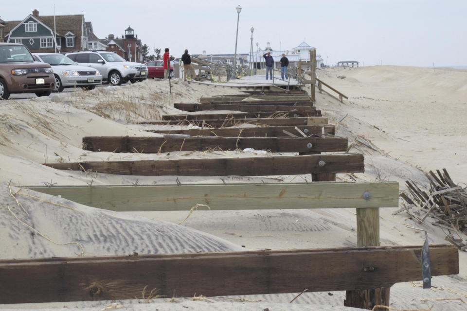 Pedestrians walk up to the edge of what had been the Sea Girt, N.J. boardwalk on Jan. 9, 2013, several months after it was destroyed by Superstorm Sandy. On Feb. 23, 2024, New Jersey selected 18 Jersey Shore towns to split $100 million in funds to repair or rebuild their boardwalks. (AP Photo/Wayne Parry)