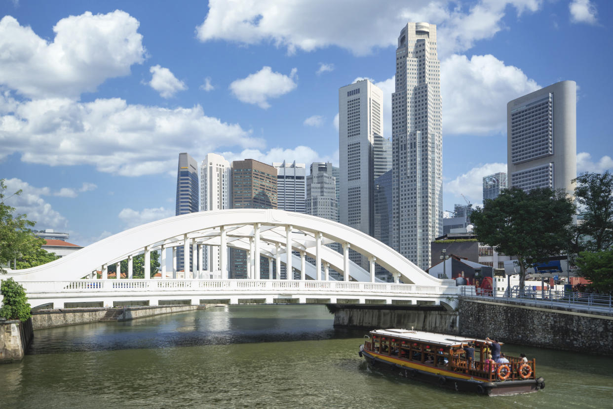 Traditional boat for tourism in Singapoer with bridge and building background.