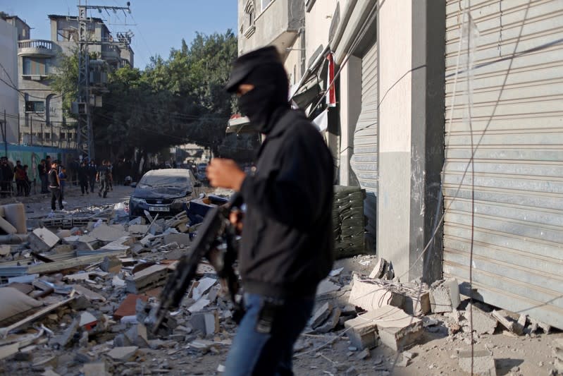 Palestinian militant stands guard outside the home of Islamic Jihad field commander Baha Abu Al-Atta after it was hit by an Israeli strike that killed him in Gaza City