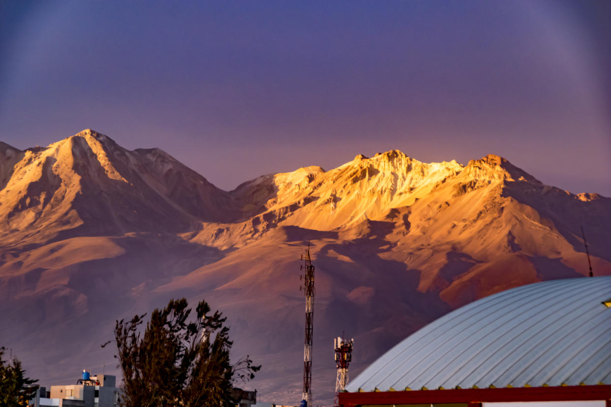 Misti and Pichu Pichu volcano seen from Arequipa Peru in a sunset. Some trees and houses are in the front of the scene