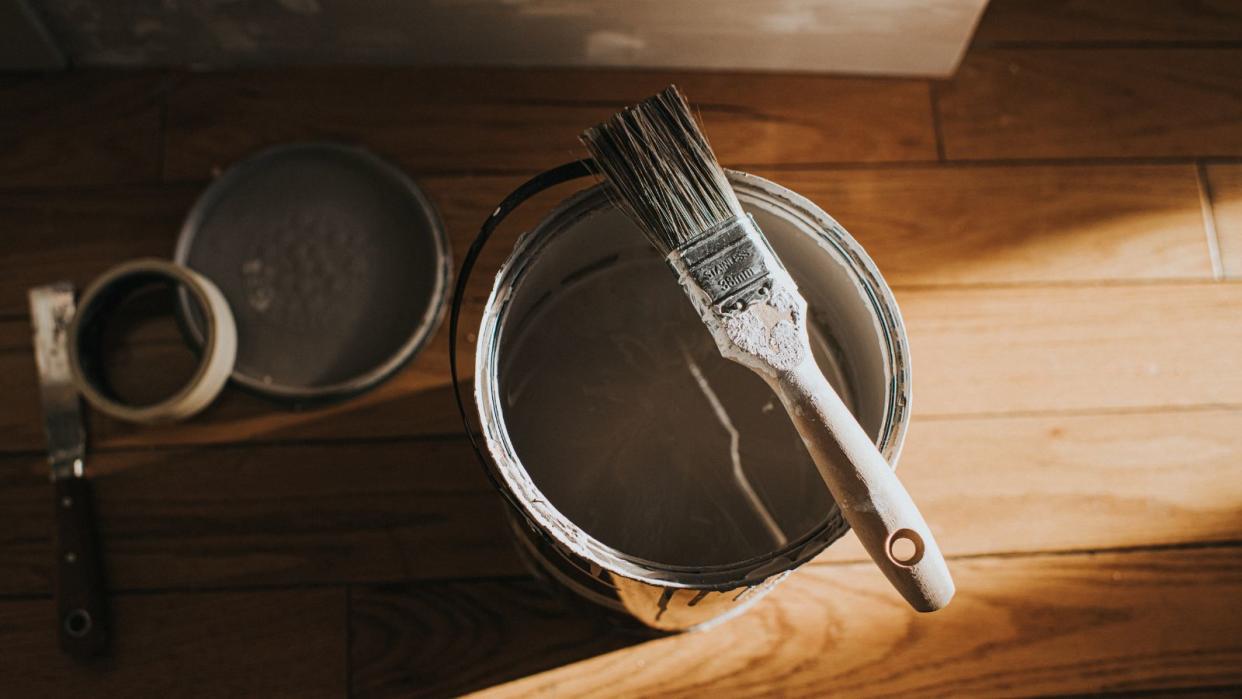  A paint tin with a paint brush resting on top 