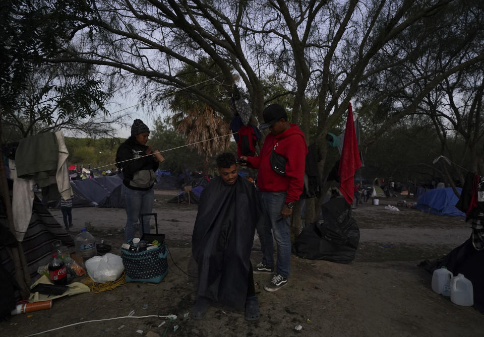 A Venezuelan migrant sits for a haircut at a makeshift camp alongside a river bank in Matamoros, Mexico, Thursday, Dec. 22, 2022. (AP Photo/Fernando Llano)