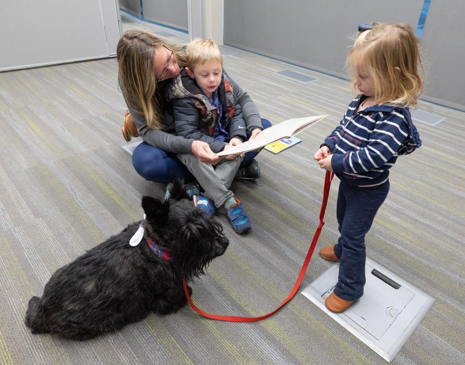Edison, 5, and mother Carissa Smock read to Gibson the Scottish terrier as sister Ella, 1, holds the leash at the Stark Library Jackson Branch's Pups and Pages program.